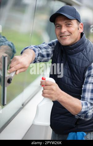 happy mature male worker cleaning glass with squeegee Stock Photo
