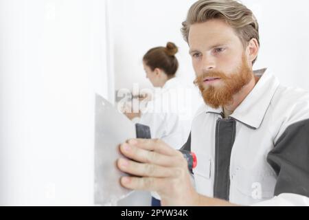 worker plastering a wall using a putty knife Stock Photo