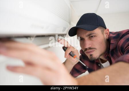 male worker checking the state of an airconditioner Stock Photo