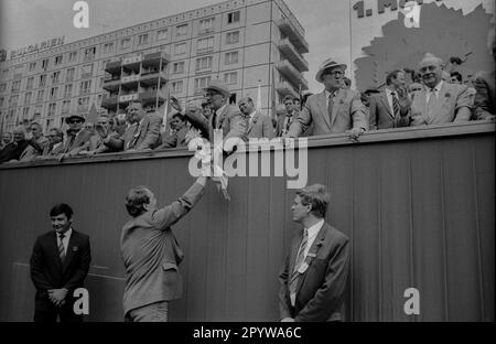 GDR, Berlin, 01.05.1987, 1. May rally 1987 on the Karl-Marx-Allee, tribune, Erich Honecker is handed flowers, left: Günter Schabowski, Horst Sindermann (2nd from right), Harry Tisch (1st from right), guards, personal security, [automated translation] Stock Photo