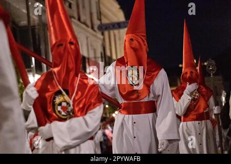 Cofradias wearing red cone shaped hoods walk through the streets during the midnight silent procession marking Good Friday at Holy Week or Semana Santa, April 6, 2023 in Ronda, Spain. Ronda, first settled in the 6th century B.C. has been holding Holy Week processions for over 500-years. Stock Photo