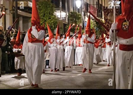 Cofradias wearing red cone shaped hoods walk through the streets during the midnight silent procession marking Good Friday at Holy Week or Semana Santa, April 6, 2023 in Ronda, Spain. Ronda, first settled in the 6th century B.C. has been holding Holy Week processions for over 500-years. Stock Photo