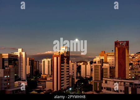 City of Belo Horizonte in the southeastern region of Brazil seen at dusk with the full moon over the buildings, Brasil Stock Photo