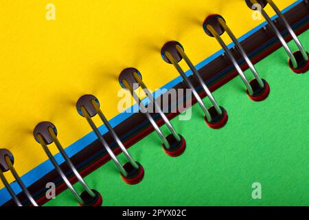 Spiral binder notebook open with green and yellow pages on display Stock Photo