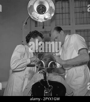 'Dentist Freese treats a patient. He is supported by a doctor. Scene from the series ''We work together''. The photographer accompanies couples in their respective occupations.' Stock Photo