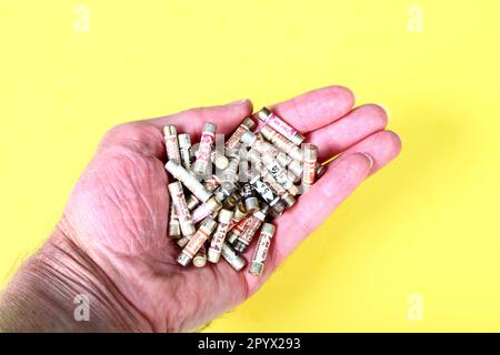 Mans hand holding a selection of electric fuses for uk plugs Stock Photo