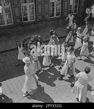 During the children's festival in in Plau in Mecklenburg, some children, accompanied by adults, take part in a parade through the streets of the city. Here, several girls in a pageant with flower wreaths and garlands (undated photo). Stock Photo