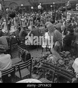 Undated photo of the garden of Cafe Europa, House of Europe, Askanischer Platz (Anhalter Bahnhof), Berlin-Kreuzberg. In the background, guests sit at the tables, or dance on the dance floor. In the front, a ceramic parrot. Stock Photo