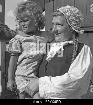 A woman carries a small child in her arms in a village on the Baltic coast in Pomerania (Kamp or Deep). Stock Photo