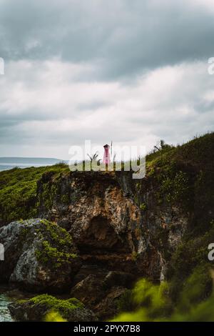 A pink lighthouse on a cliff overlooking the vast ocean in Saipan Stock Photo