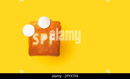 Concept of SPF cream on toasted bread. Yellow background. Stock Photo