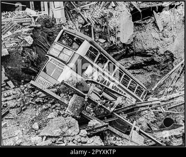 WW2 The London Blitz with a London bus in a bomb crater after a terror bombing blitz by Nazi Germany. The aftermath of a bombing raid, a bus lies in a crater in Balham, South London. Air Raid Damage in Britain during the Second World War. World War II Stock Photo