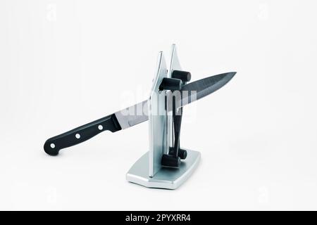 a kitchen knife in a desktop knife sharpener, on a white background Stock Photo