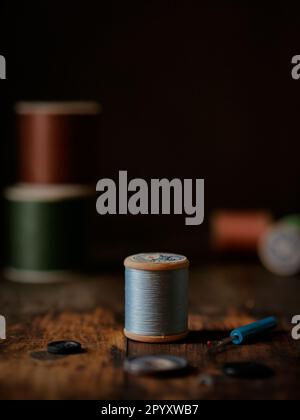 Multicolor sewing threads on wooden table with dark background Stock Photo