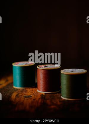 Multicolor sewing threads on wooden table with dark background Stock Photo