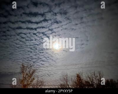 A bright moon shining through a mackerel sky. Stock Photo