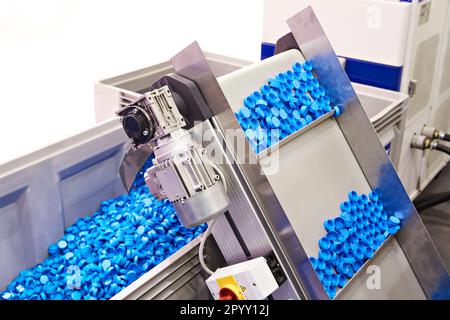 Conveyor on machine for production of plastic cap for bottles Stock Photo