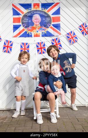 Halesowen, West Midlands, UK. 5th May, 2023. Four young excited brothers outside their family's garage door decorated ready for the coronation day of King Charles III in Halesowen, West Midlands. Credit: Peter Lopeman/Alamy Live News Stock Photo