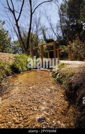 A vertical shot of a small but powerful stream of clear, sparkling water flowing down a rocky terrain Stock Photo