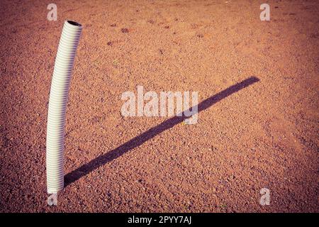 Flexible plastic pipe with electric cable coming out from the ground - toned image with copy space Stock Photo