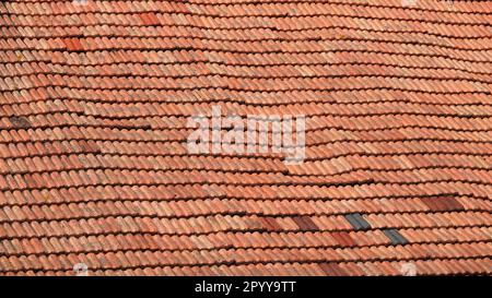 A wavy roof with old tiles. Everything in good condition. Orange background Stock Photo