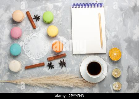 top view cup of tea with french macarons on white desk cake biscuit sweet cookie Stock Photo