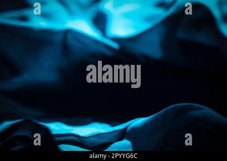 Blue fabric crumpled in the rays of light and shadows as a background, blue Stock Photo