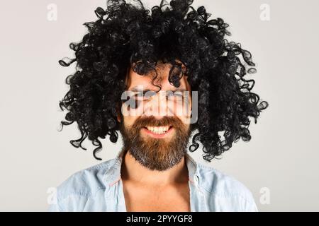 Bearded man in black wig. Angry man with beard and mustache in curly wig. Bearded hipster in black curly afro wig. Male in periwig. Party time. Barber Stock Photo