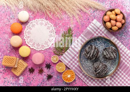 top view yummy chocolate cakes with macarons and waffles on pink background sugar cookies biscuit pie sweet Stock Photo