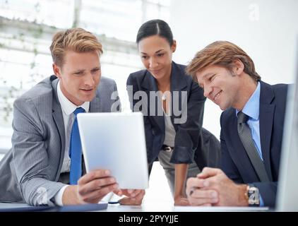 What do you think. A young businessman showing his co-workers something on a digital tablet. Stock Photo
