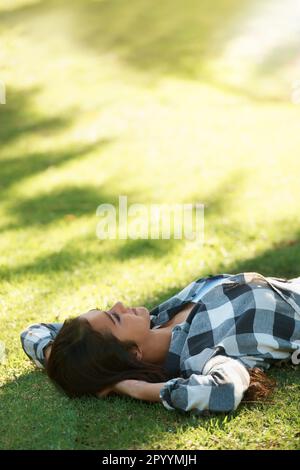 Leisure time in the park. Young woman lying on the grass in a park. Stock Photo