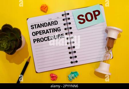 SOP - Standard Operating Procedure, text on notepad and office accessories on yellow desk Stock Photo