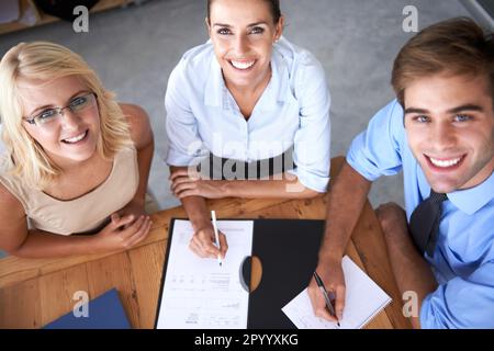 Getting my teams input. Three young executives sitting around a table discussing paperwork. Stock Photo