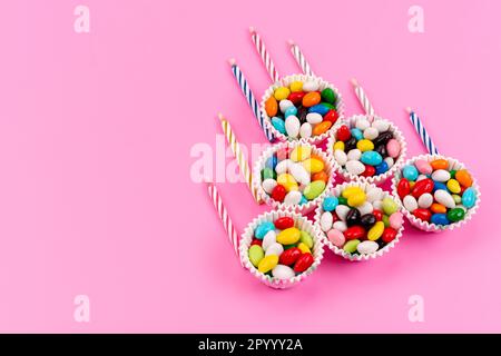 a top view colorful candies inside paper packages along with candles on the pink background sugar rainbow color Stock Photo