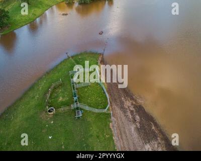Floodwaters on farmland creeping towards cattle yards seen from aerial view Stock Photo