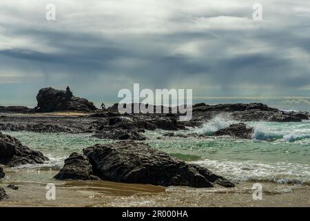 View of the rocky shore and rain showers over the sea on an autumn day, at Currumbin Beach, Gold Coast, Queensland, Australia Stock Photo