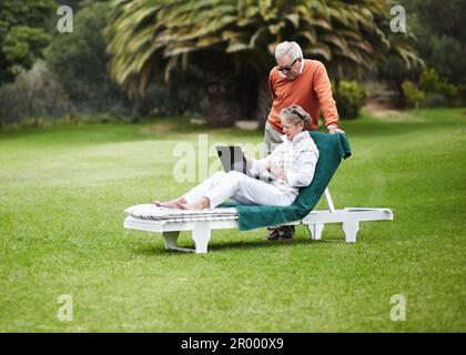 Keeping in contact on their getaway. A senior couple using a laptop while on vacation. Stock Photo