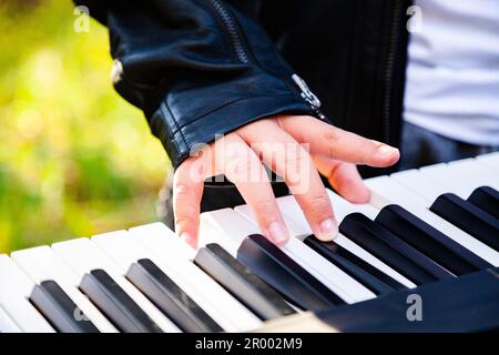 boys hands pressing keys to play music on keyboard outside Stock Photo