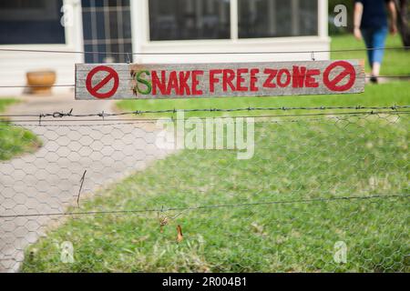 Snake free zone sign hanging on farm fence - australian humour - because snakes can't read Stock Photo