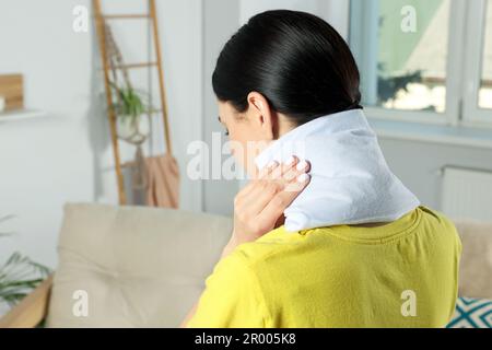 Woman using heating pad on neck at home Stock Photo