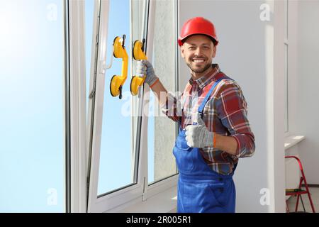 Worker using suction lifters during plastic window installation indoors Stock Photo