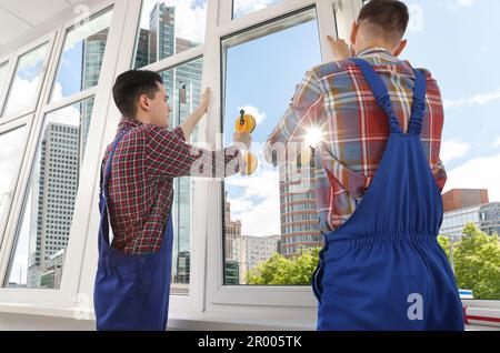 Workers using suction lifters during plastic window installation indoors Stock Photo