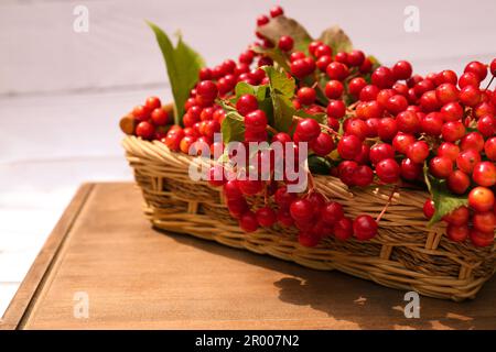 Wicker basket with ripe red viburnum berries on table, closeup Stock Photo