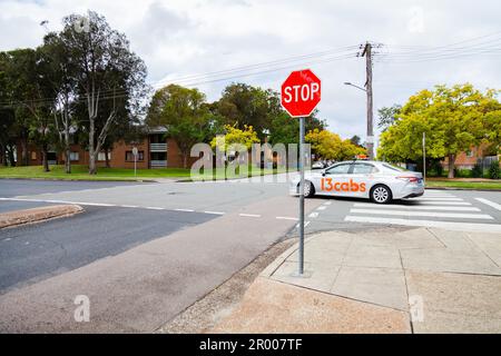 13 caps taxi driving through intersection in Hamilton South suburb of Newcastle Stock Photo