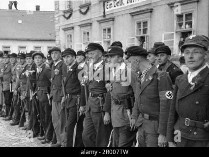 Members of the Sudeten-German Volontary Corps are standing by to greet Hitler upon his arrival in Niemes after the annexation of the Sudetenland. After the annexation of Austria, Hitler demanded that he be given the Sudeten region of Czechoslovakia. At the Munich conference in September 1938 the Western powers agreed to this and the nazis occupied the area. Not long after Hitler broke his promise and invaded the rest of Czechoslovakia before turning his attention to Poland. Bundesarchiv, Bild 146-1972-026-51 / CC-BY-SA 3.0 Stock Photo