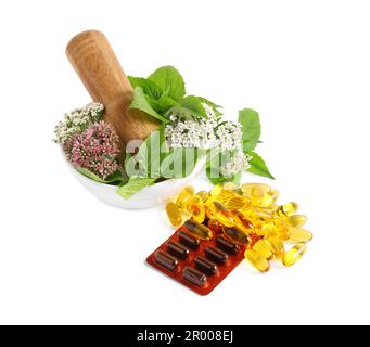 Mortar with fresh herbs and pills on white background Stock Photo