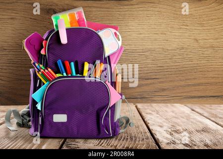 Backpack with school stationery on table against wooden background, space for text Stock Photo