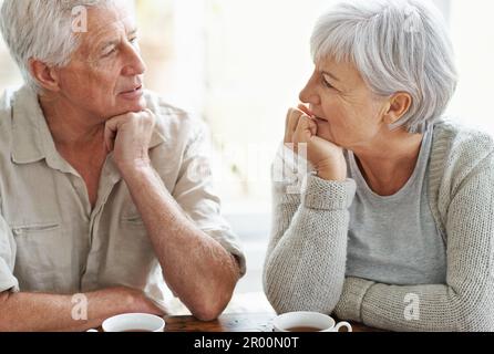 Senior couple, talking and drinking tea in home for conversation, communication and quality time together. Old man, elderly woman and chat with cup of Stock Photo
