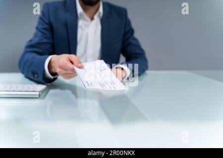 Close-up Of A Human Hand Giving Cheque On Desk Stock Photo
