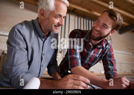 Architecture, teamwork and man with apprentice in workshop for collaboration. Senior engineer, men and smile with trainee, working on remodeling Stock Photo